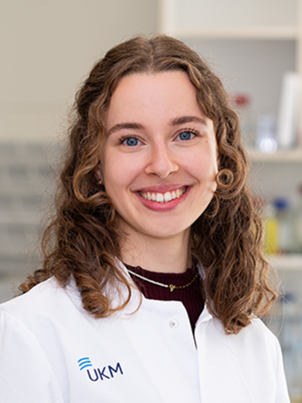 UKM | Portraitaufnahme einer Mitarbeiterin im Forschungsteam der Klinik für Endovaskuläre und Vaskuläre Chirurgie | Sie trägt einen weißen Kittel und lächelt