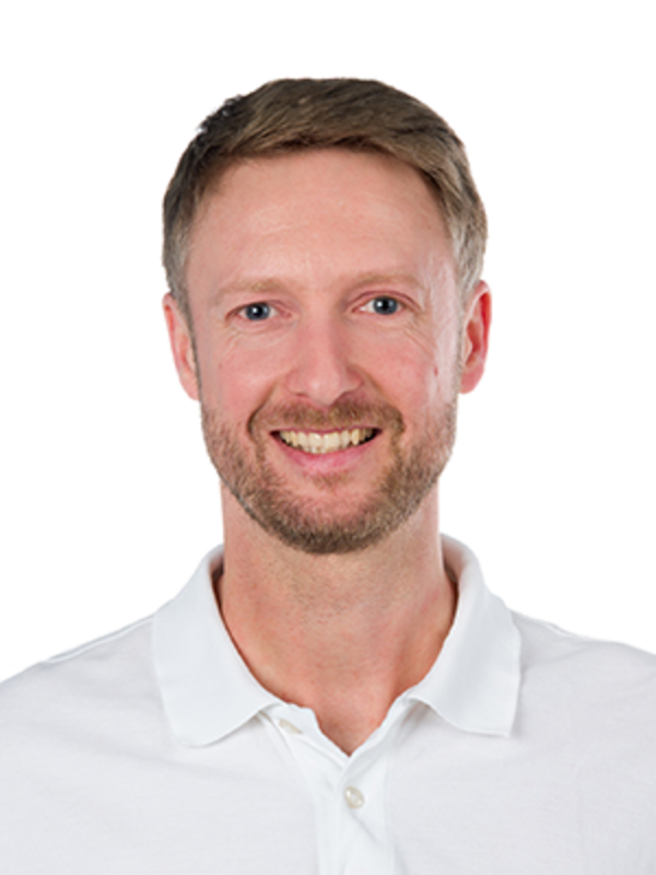 UKM | Portrait von Max Tönnemann aus der Orthopädie. Er trägt ein weißes Hemd und lacht.