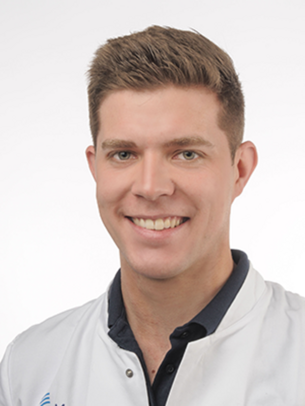 UKM | Arzt aus der Unfallchirurgie. Er trägt einen weißen Kittel und lacht.