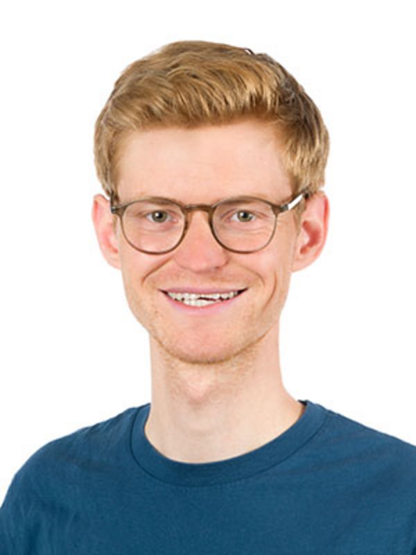 UKM Kinder- und Jugendpsychiatrie | Henning Elpers | Er trägt einen dunkelblauen Pullover, eine Brille und lächelt in die Kamera.