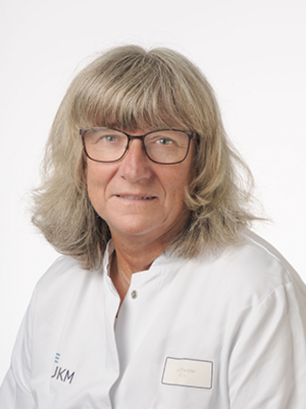 UKM | Portraitfoto einer Medizinisch-technischen Assistentin aus der Angiologie. Sie trägt einen weißen Kittel, eine Brille und lächelt.