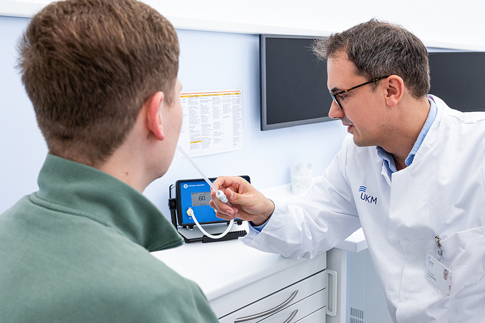 UKM | Arzt im weißen Kittel erklärt einem Patienten ein Gerät zur Bestimmung von Mundgeruch.