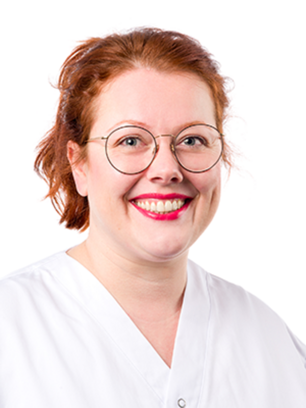 UKM | Portrait einer Dentalhygienikerin der Klinik für Parodontologie. Sie trägt eine Brille, einen weißen Kasack und lächelt.