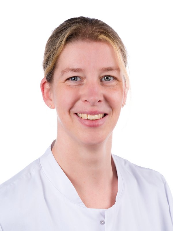 Frau im weißen Kittel, die lächelt.