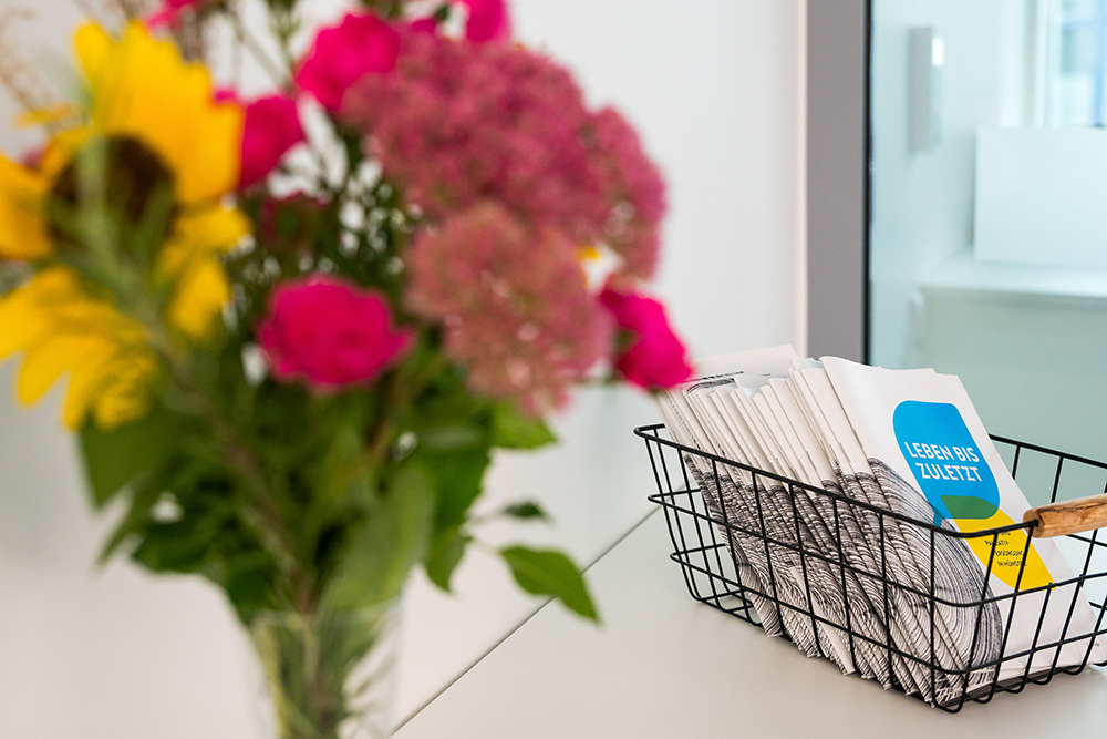 UKM | Blumenstrauß auf der Palliativstation sowie Flyer in einem Körbchen